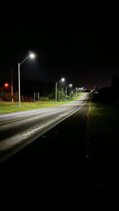 A row of luminaires along a highway at night.